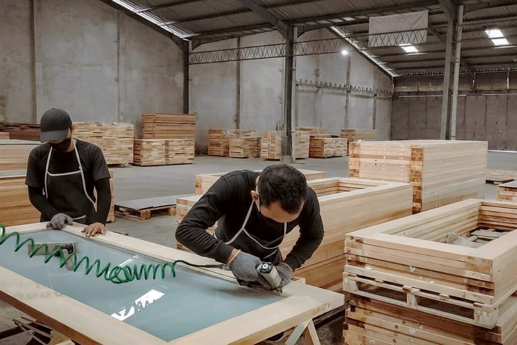 Skilled Indonesian craftsman hand-sanding solid wood door surface for smooth finish